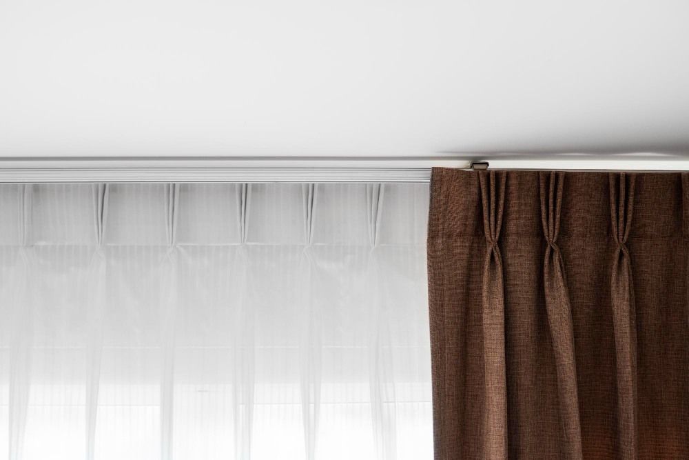 Rideaux bruns et tulle blanc sur un rail avec un plafond blanc
